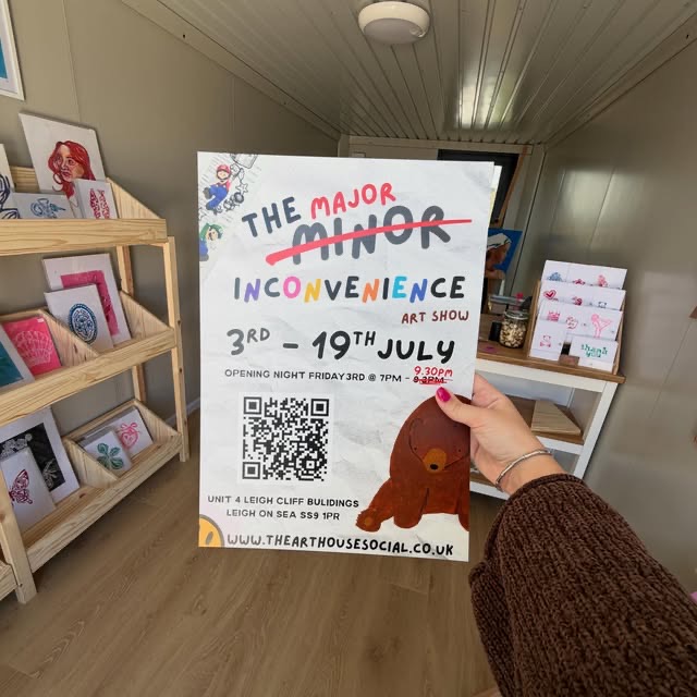 Alice holding the poster for The Major Minor Inconvenience art show
